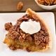 Slice of pecan pie with whipped cream on a white plate